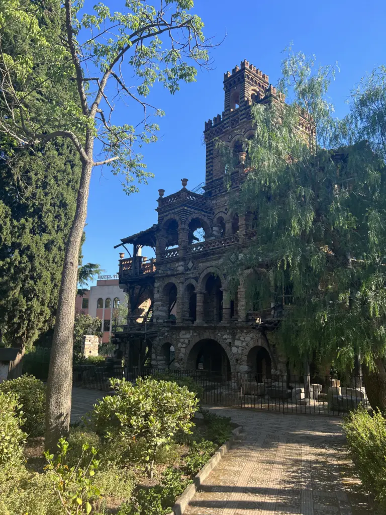 Neugotisches Steingebäude zwischen Bäumen im Park von Taormina