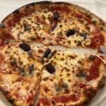 Pizza with olives on a white plate