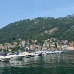 Boats moored in a lakeside harbour below green hills