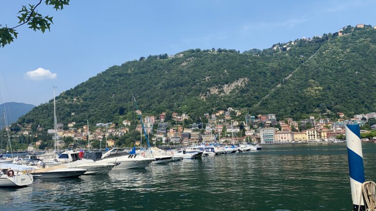 Boats moored in a lakeside harbour below green hills