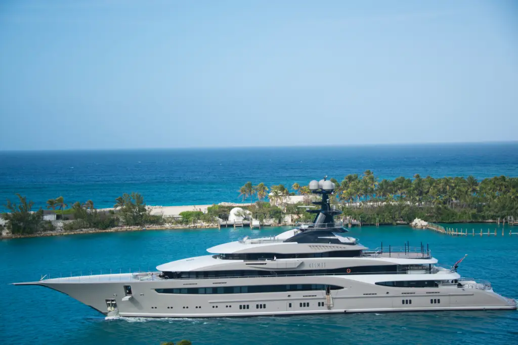 Large white motor yacht anchored in turquoise water near an island