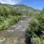 Shallow mountain stream with a footbridge among green hills