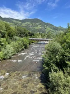 Shallow mountain stream with a footbridge among green hills