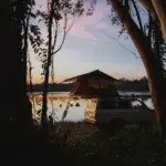 Zelt und Auto beim Camping an einem See bei Sonnenuntergang
