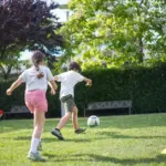 Kinder spielen Fußball auf einem Gartenrasen