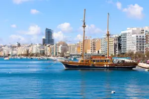 Wooden sailing ship in Sliema harbour in front of modern buildings