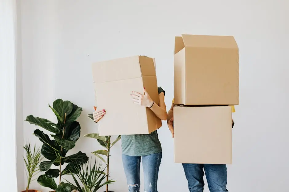 Two people carrying moving boxes that hide their faces