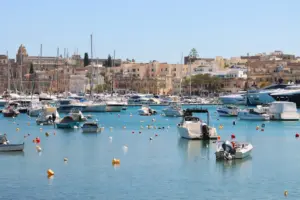 Boats moored in a Maltese harbour in front of limestone town