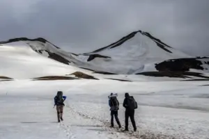 Hikers crossing a snowfield towards a volcano summit