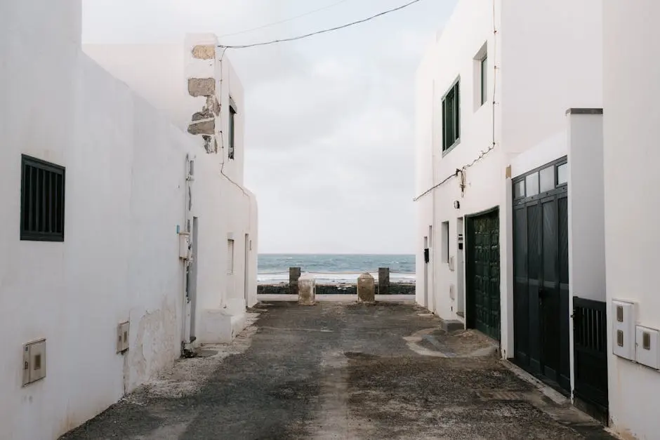 Schmale Küstengasse zwischen weißen Häusern mit Blick aufs Meer