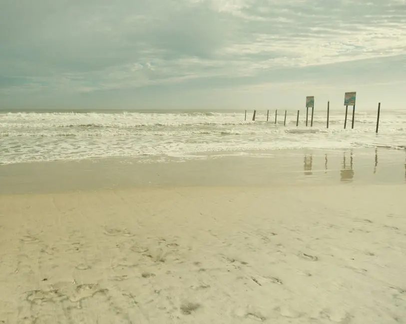 Ruhige Wellen spülen über einen Sandstrand unter bewölktem Himmel