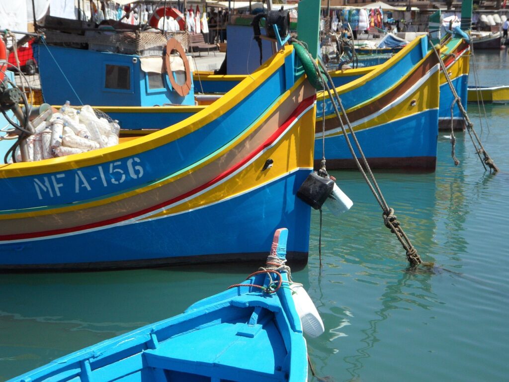 Colourful luzzu fishing boats moored in Marsaxlokk harbour, Malta