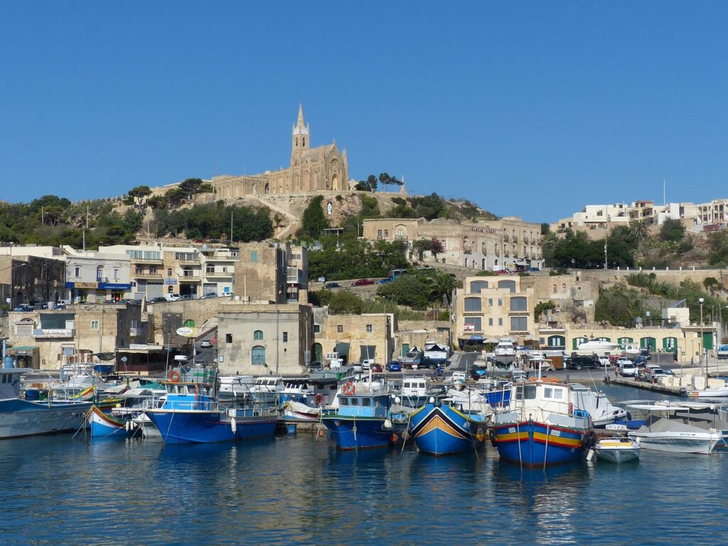 Fishing boats and the church above Mgarr harbour on Gozo, Malta