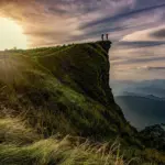 Hikers on a grassy cliff at sunrise in Chiang Rai province