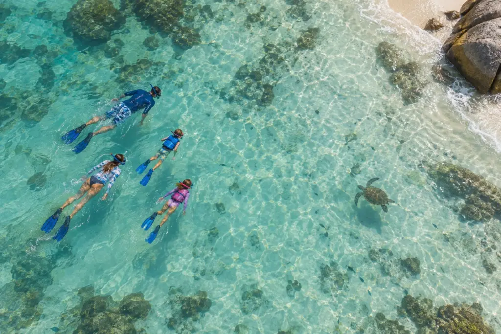 Kind beim Schnorcheln im flachen türkisen Wasser auf den Seychellen (KI-generiert)